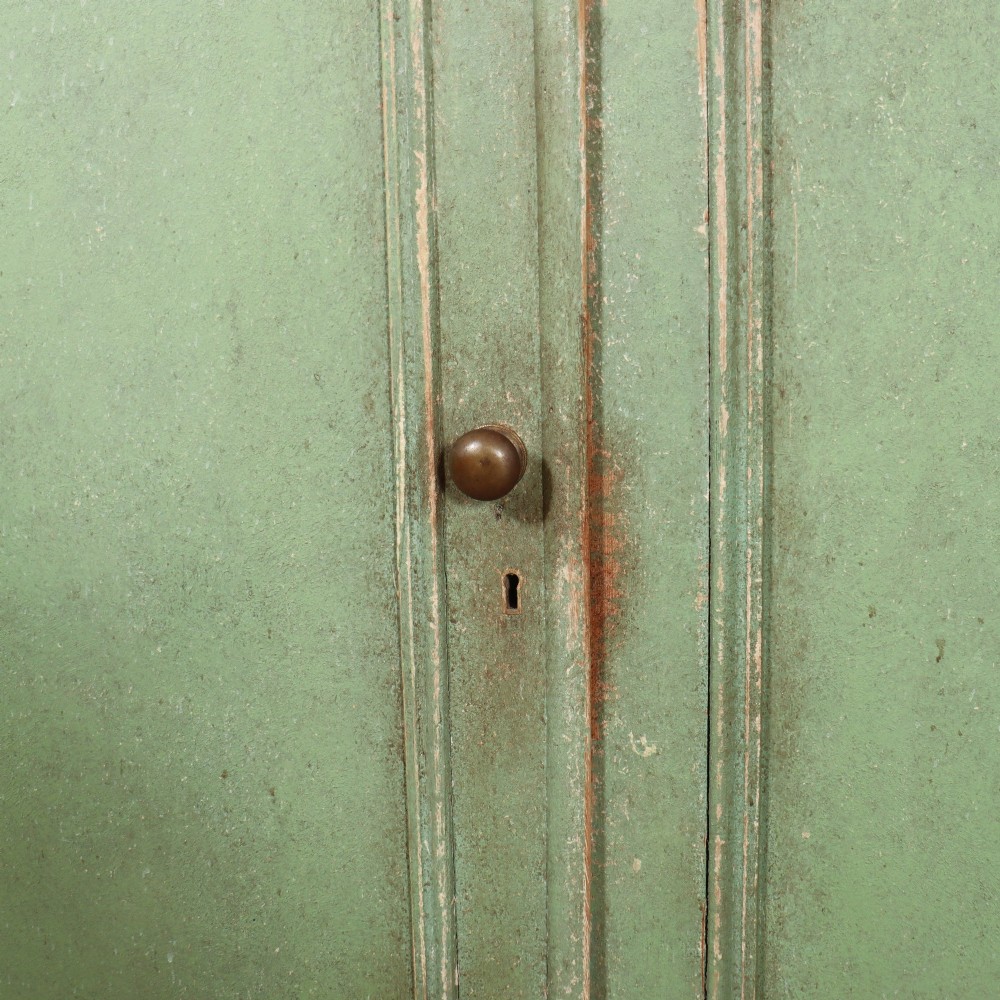 A two-part antique green painted wood kitchen dresser featuring a three-door glazed upper cabinet and three panelled cupboard doors below. View VIII