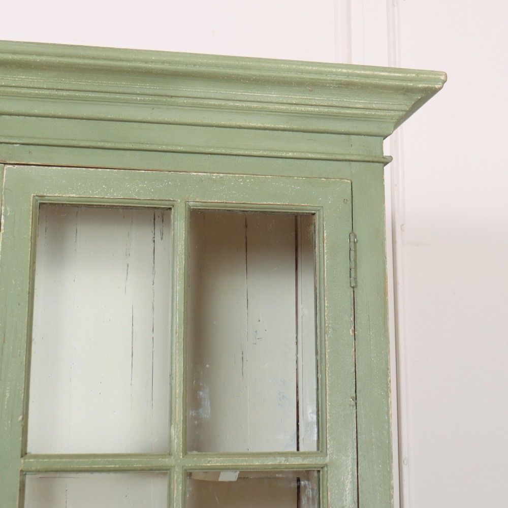 A tall 19th-century English painted sage green glazed display bookcase with two glass panel doors and an off-white interior. View III