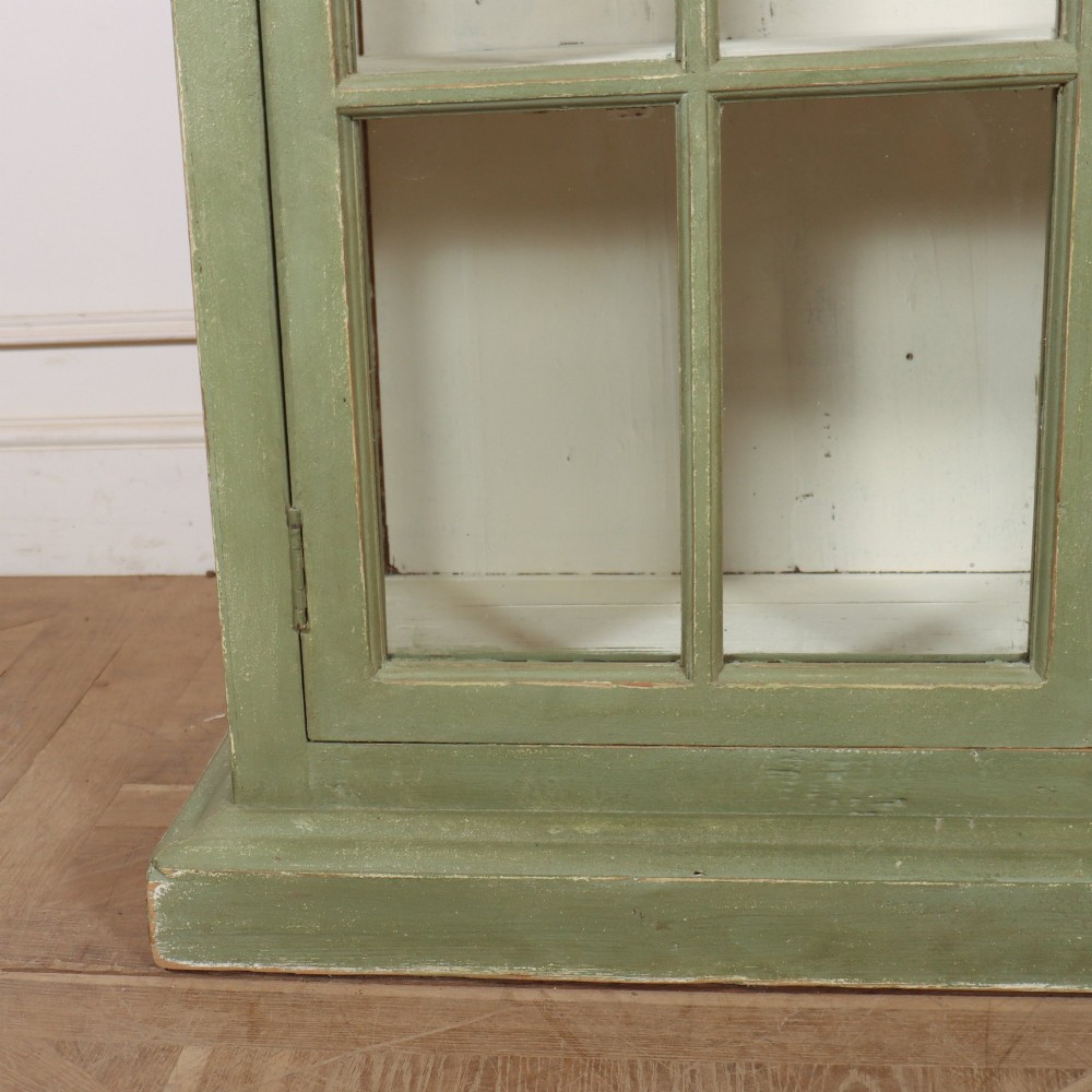 A tall 19th-century English painted sage green glazed display bookcase with two glass panel doors and an off-white interior. View IV