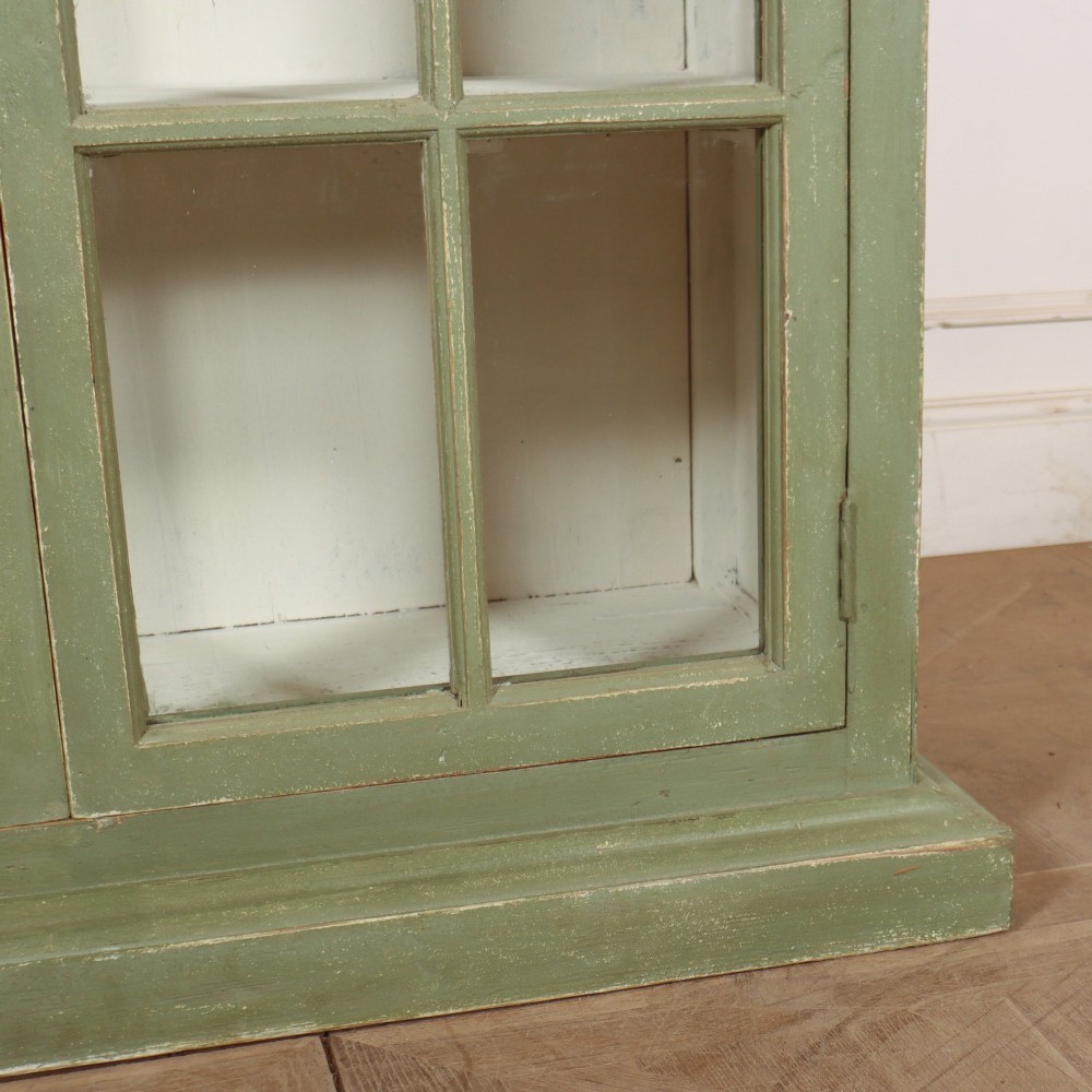 A tall 19th-century English painted sage green glazed display bookcase with two glass panel doors and an off-white interior. View V