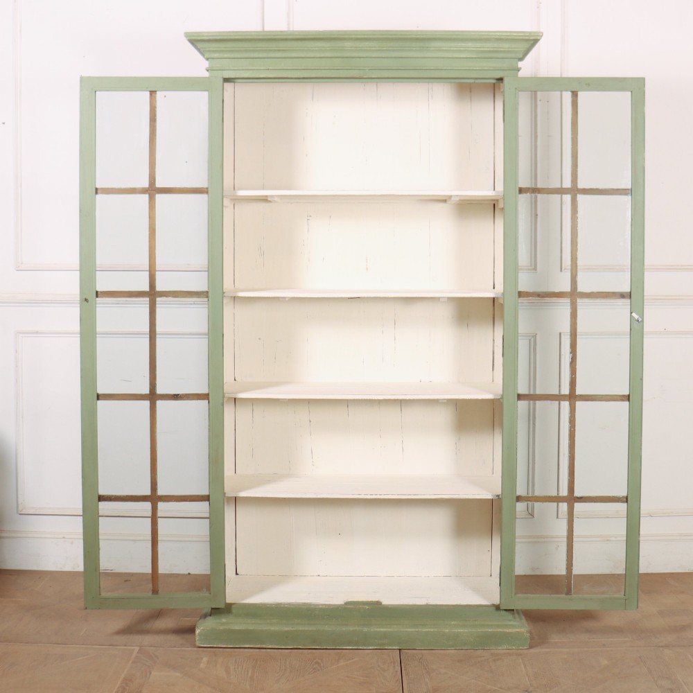 A tall 19th-century English painted sage green glazed display bookcase with two glass panel doors and an off-white interior. View VII