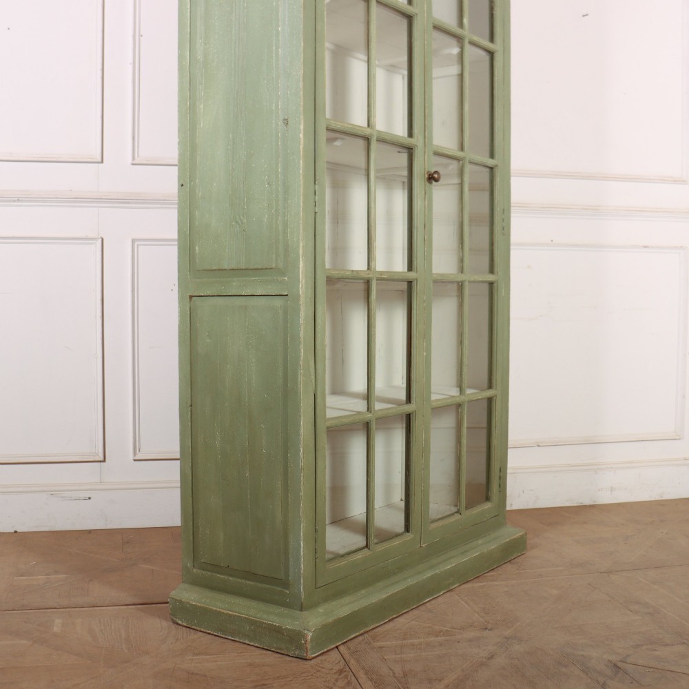 A tall 19th-century English painted sage green glazed display bookcase with two glass panel doors and an off-white interior. View XI
