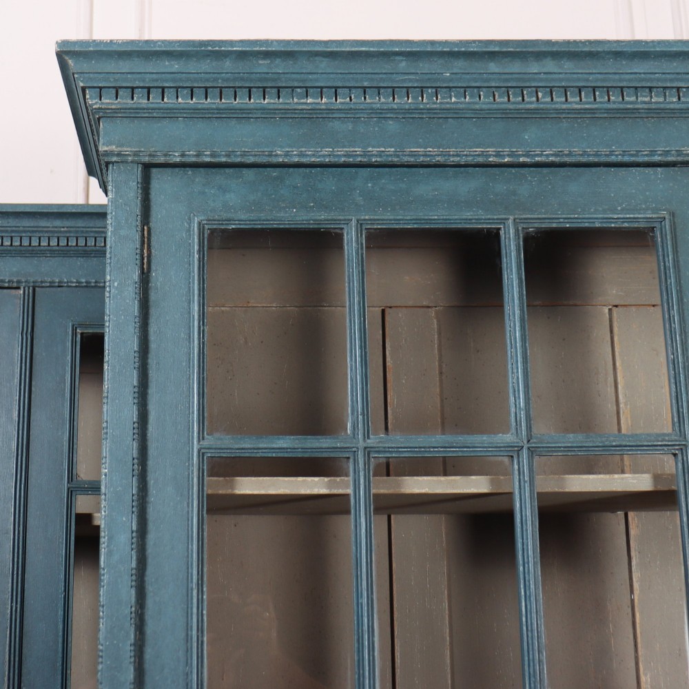 A pair of tall English glazed library bookcases painted in a muted teal blue finish with contrasting light interior shelves and glass grid doors. View IV