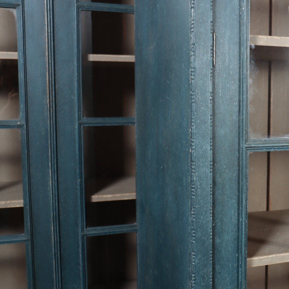 A pair of tall English glazed library bookcases painted in a muted teal blue finish with contrasting light interior shelves and glass grid doors. View V