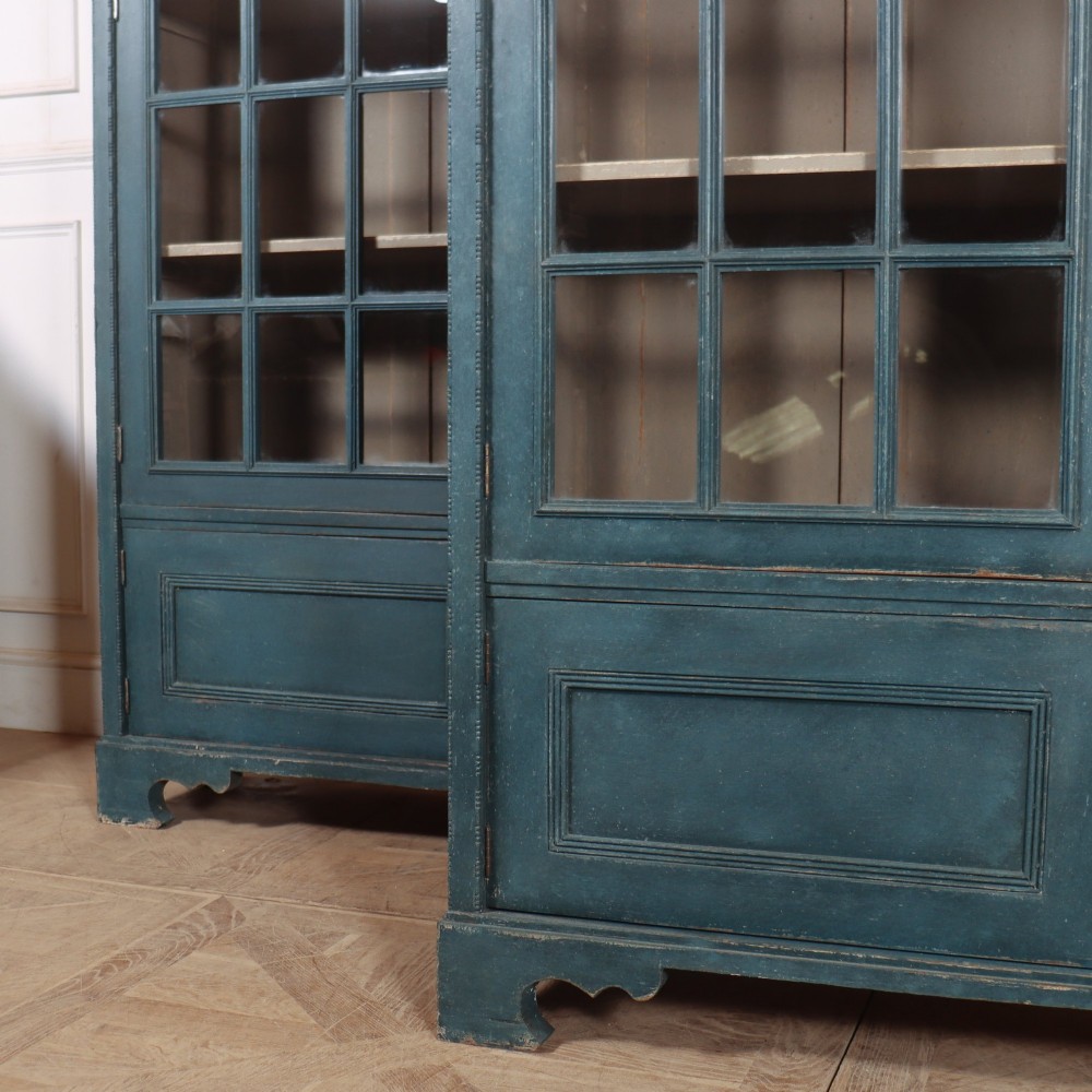 A pair of tall English glazed library bookcases painted in a muted teal blue finish with contrasting light interior shelves and glass grid doors. View VIII