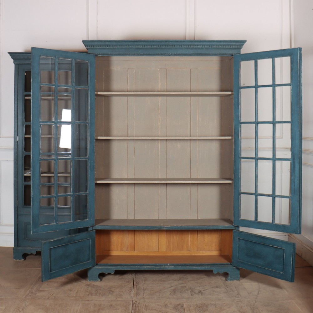 A pair of tall English glazed library bookcases painted in a muted teal blue finish with contrasting light interior shelves and glass grid doors. View IX