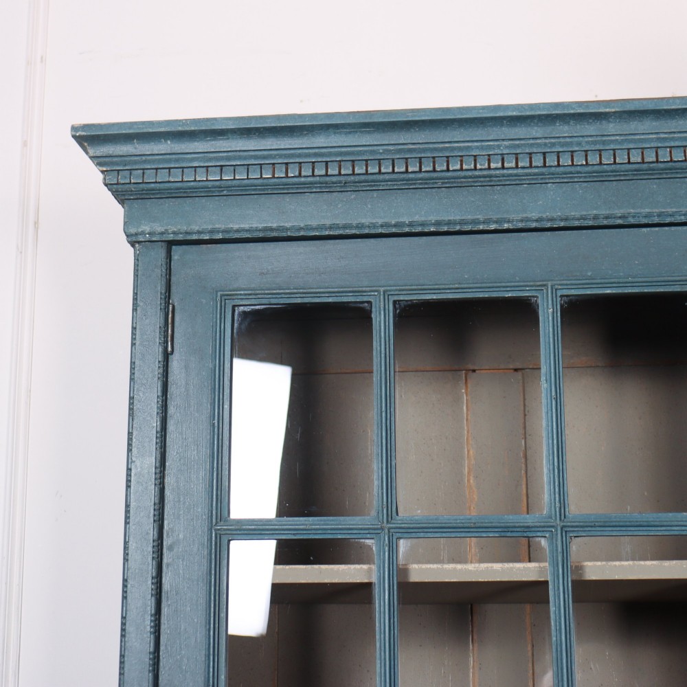 A pair of tall English glazed library bookcases painted in a muted teal blue finish with contrasting light interior shelves and glass grid doors. View XI