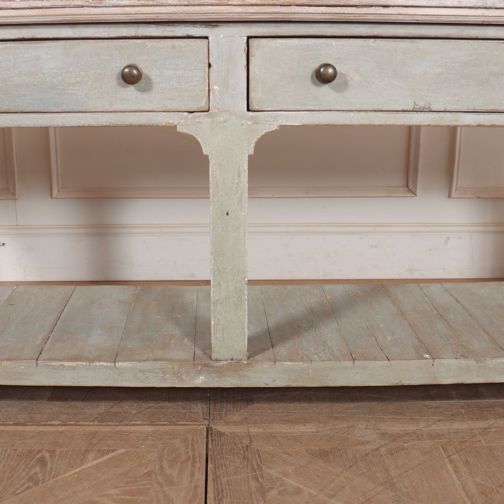 An English painted wooden potboard dresser base with a scrubbed timber top, two drawers, turned legs, and an open slatted lower shelf. View V
