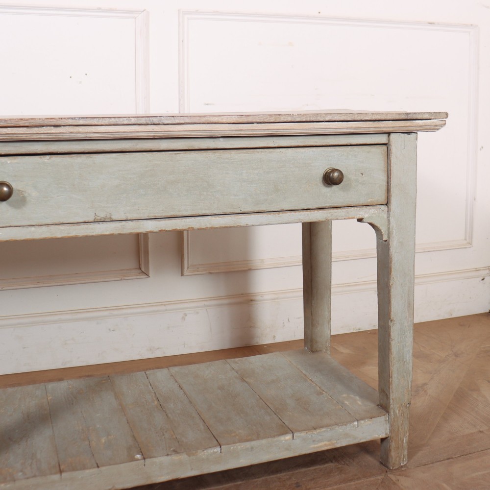An English painted wooden potboard dresser base with a scrubbed timber top, two drawers, turned legs, and an open slatted lower shelf. View VI