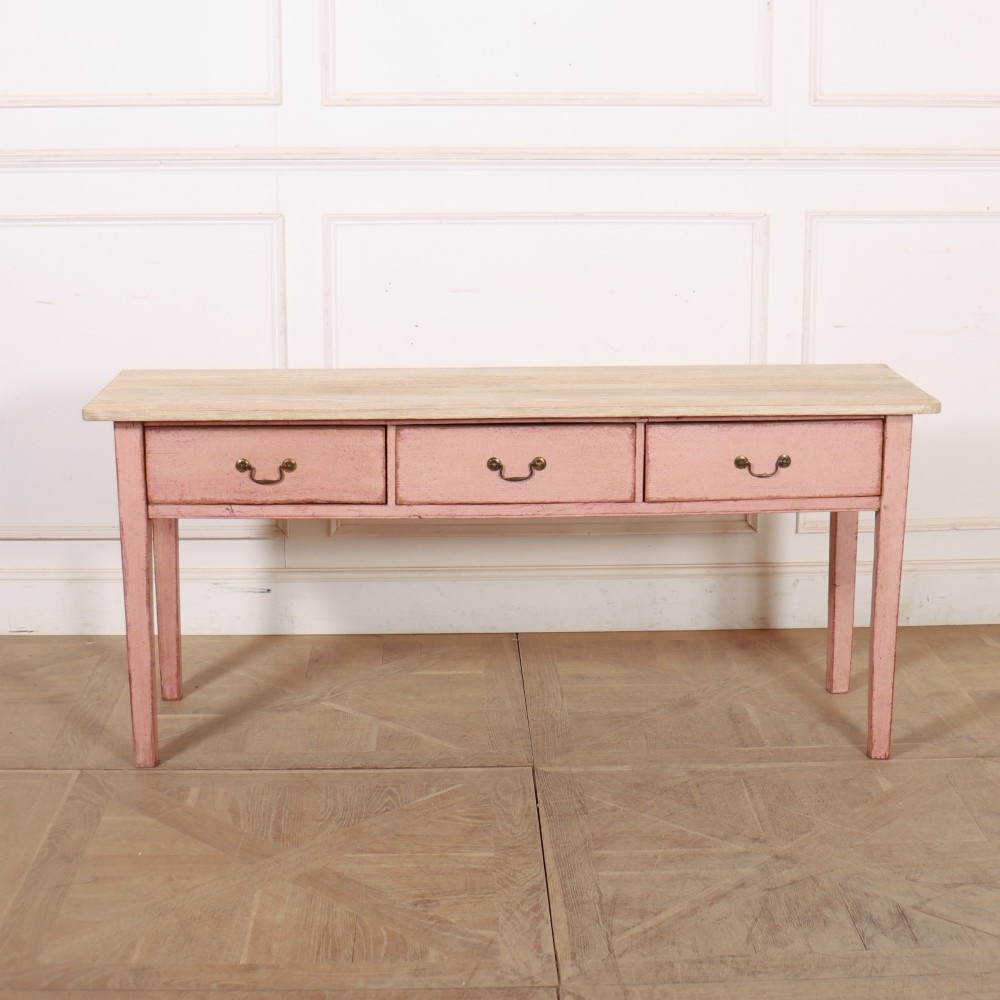 An antique English wooden server featuring a scrubbed natural timber top, a distressed pink painted frame, three drawers with brass drop handles, and four straight legs. View II