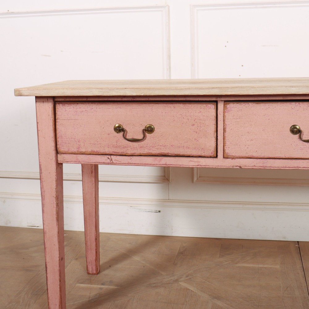 An antique English wooden server featuring a scrubbed natural timber top, a distressed pink painted frame, three drawers with brass drop handles, and four straight legs. View III
