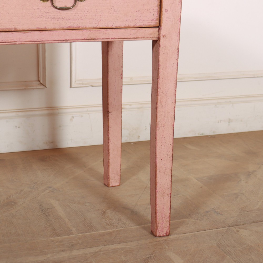 An antique English wooden server featuring a scrubbed natural timber top, a distressed pink painted frame, three drawers with brass drop handles, and four straight legs. View VII