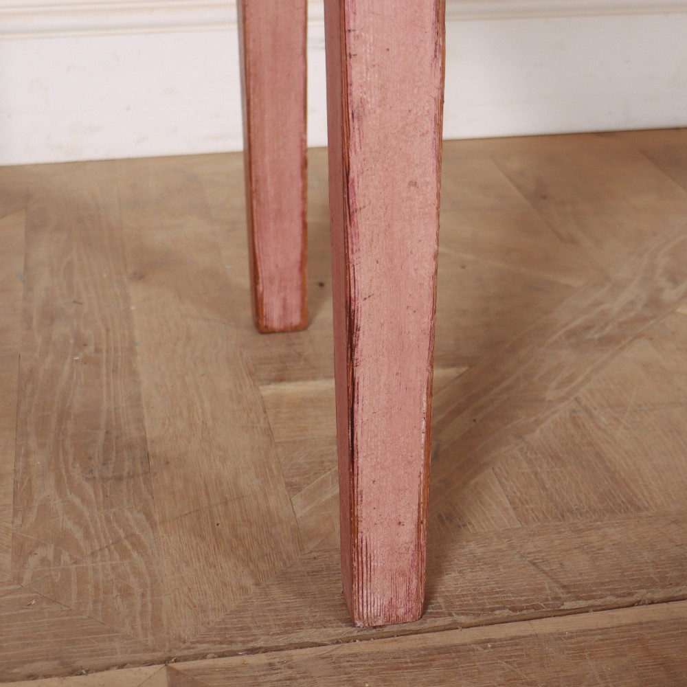 An antique English wooden server featuring a scrubbed natural timber top, a distressed pink painted frame, three drawers with brass drop handles, and four straight legs. View VIII