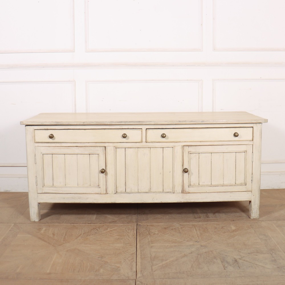An English painted wood dresser base featuring two long top drawers with brass knob handles above panelled cupboard doors.