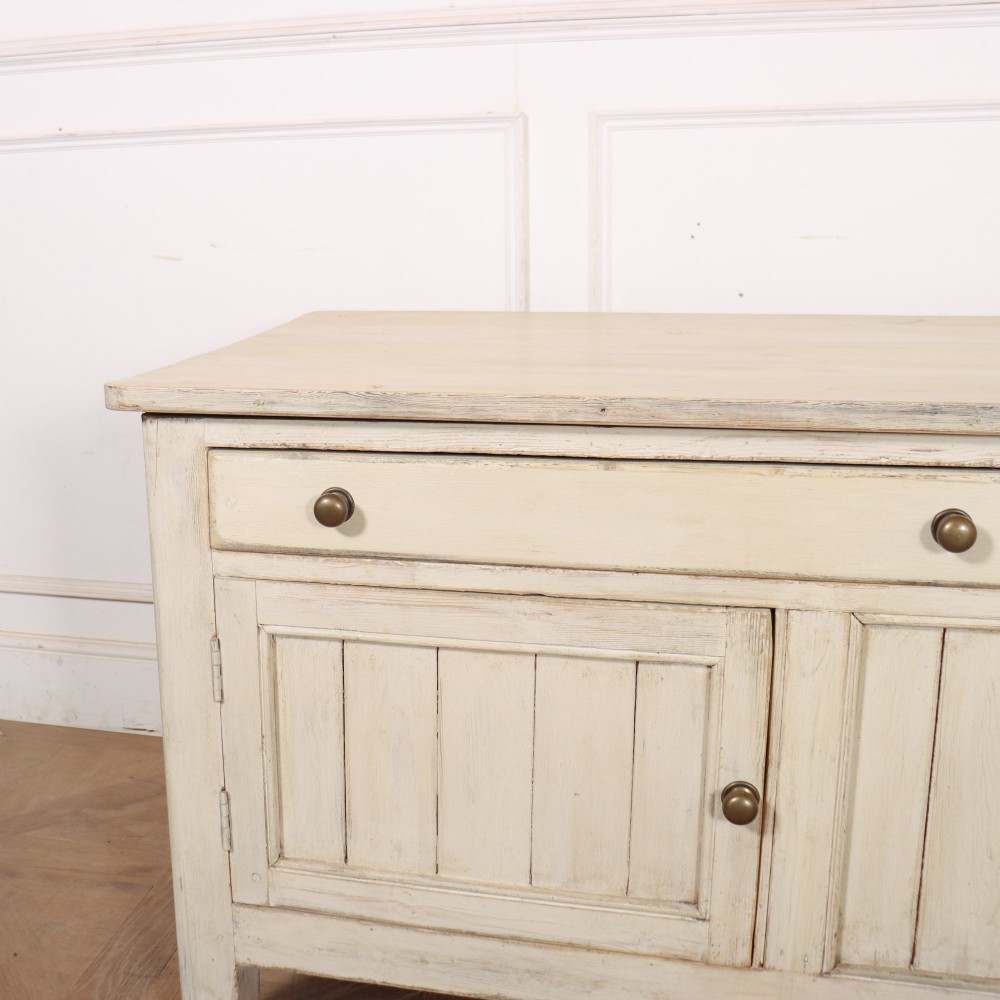 An English painted wood dresser base featuring two long top drawers with brass knob handles above panelled cupboard doors. View II