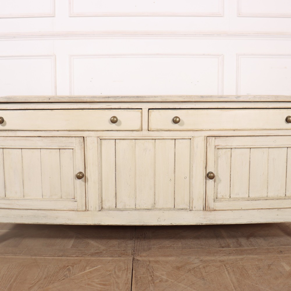 An English painted wood dresser base featuring two long top drawers with brass knob handles above panelled cupboard doors. View IV