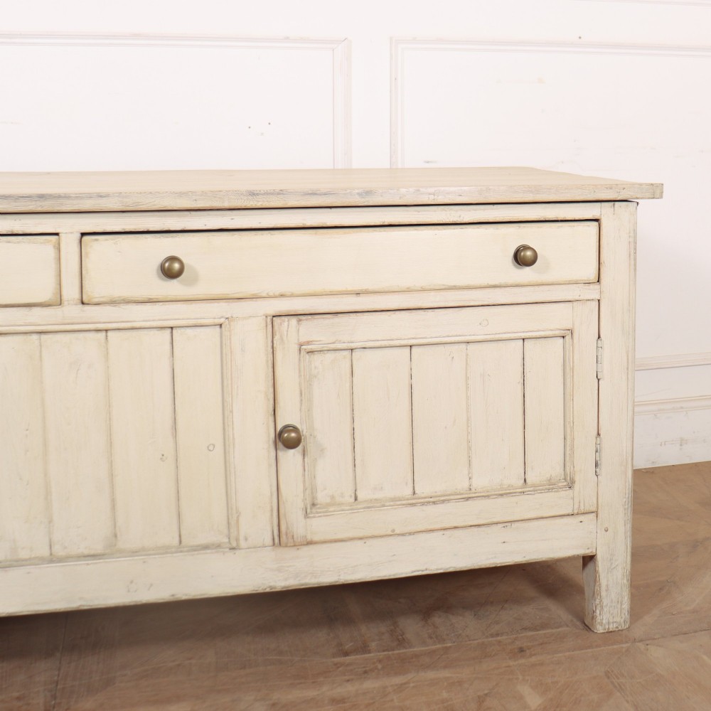 An English painted wood dresser base featuring two long top drawers with brass knob handles above panelled cupboard doors. View V