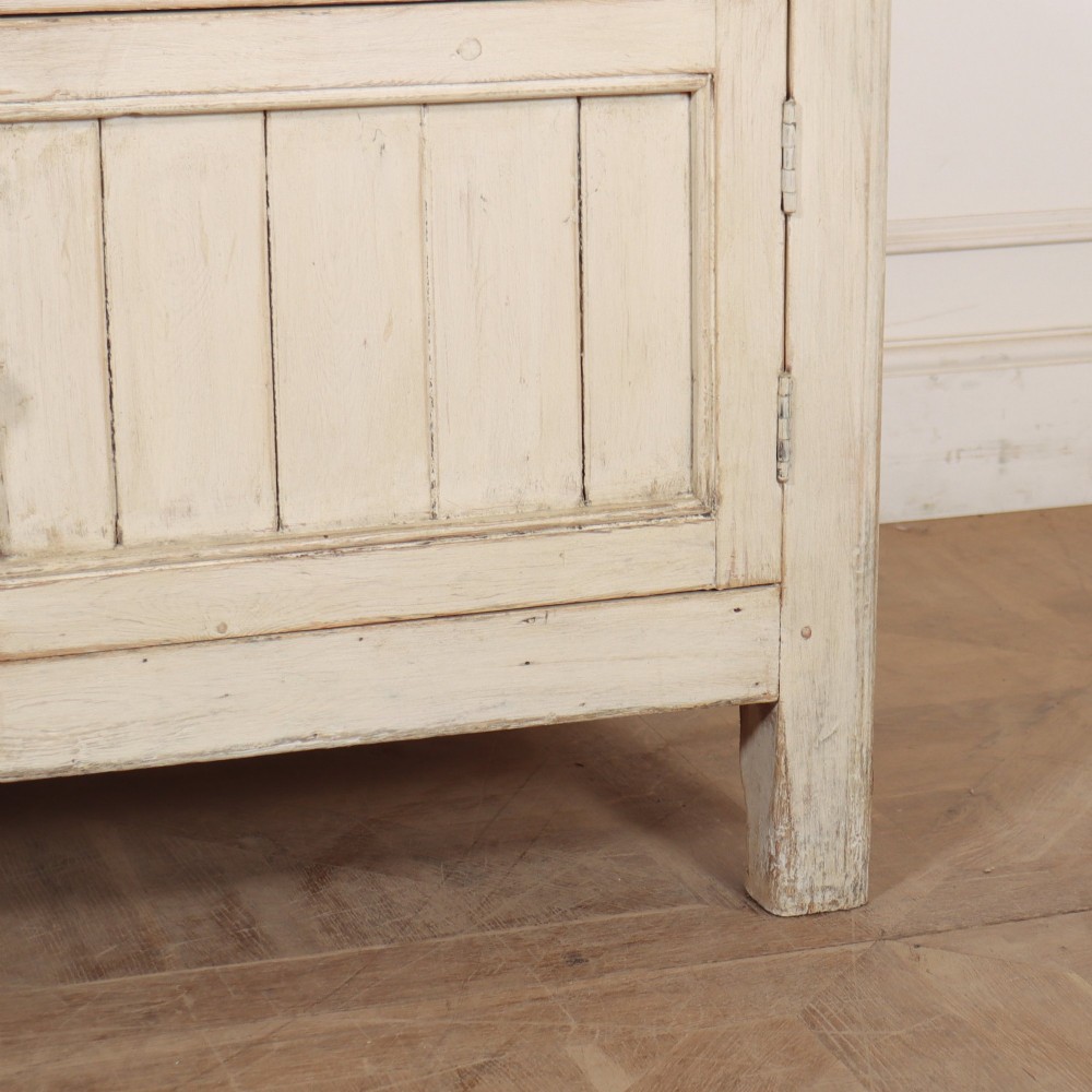 An English painted wood dresser base featuring two long top drawers with brass knob handles above panelled cupboard doors. View VI