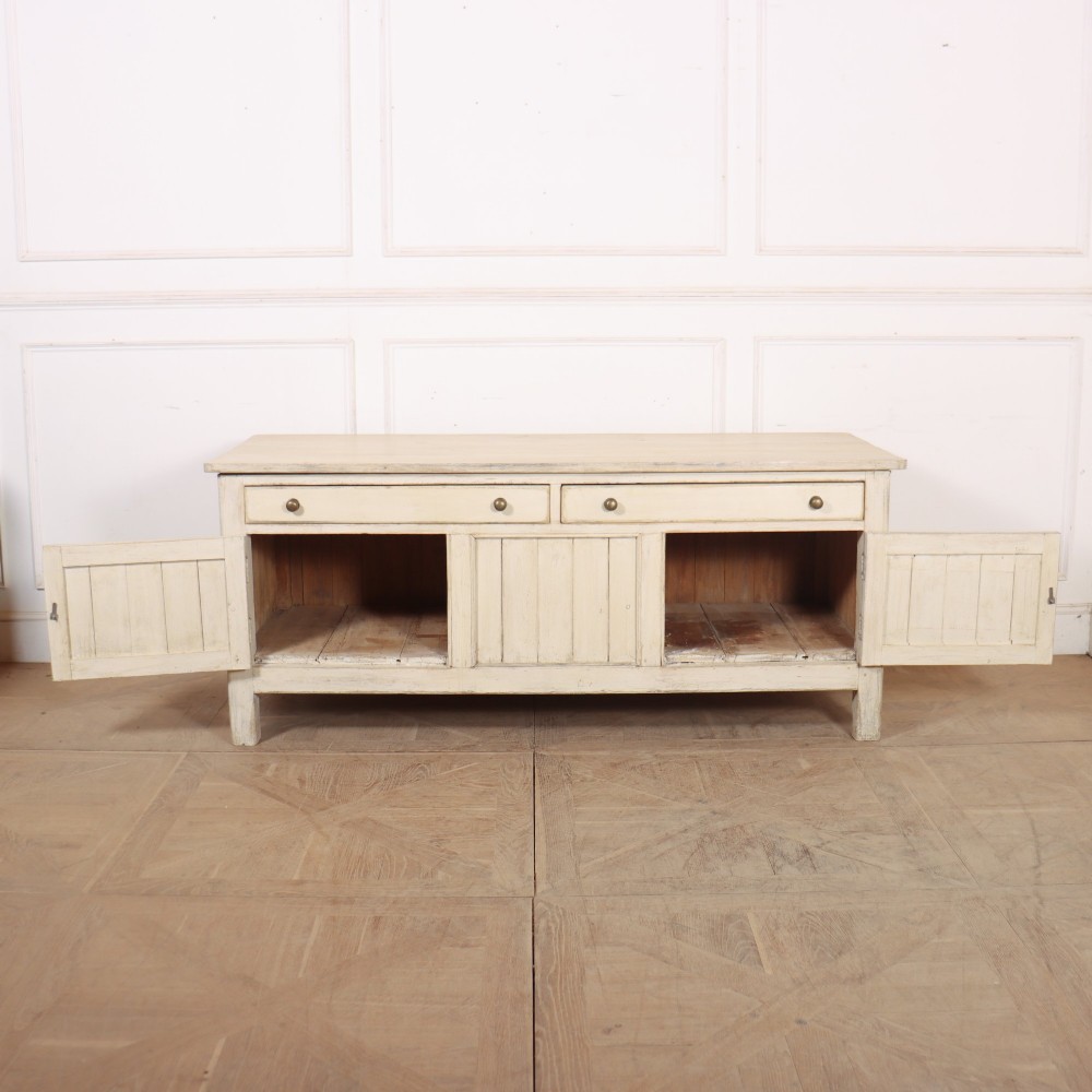 An English painted wood dresser base featuring two long top drawers with brass knob handles above panelled cupboard doors. View VII