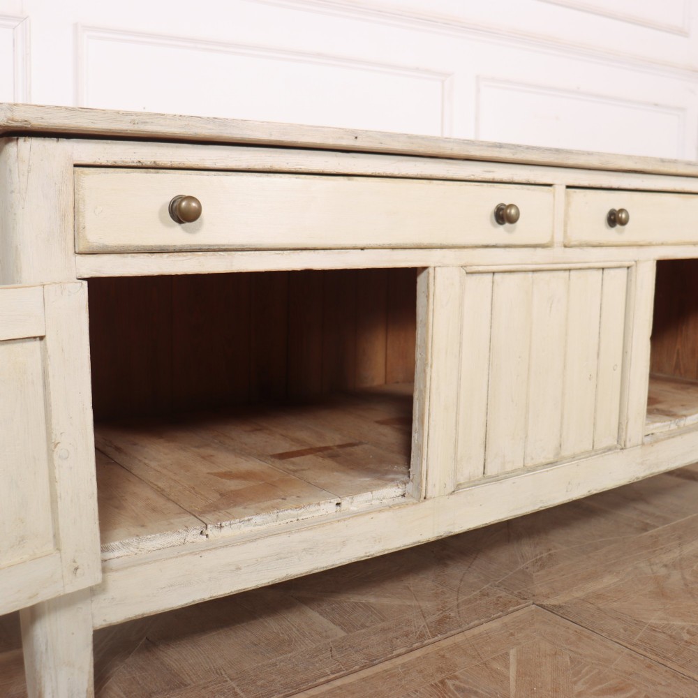 An English painted wood dresser base featuring two long top drawers with brass knob handles above panelled cupboard doors. View VIII