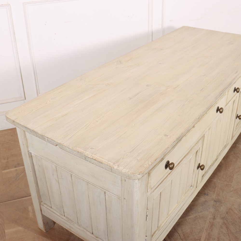 An English painted wood dresser base featuring two long top drawers with brass knob handles above panelled cupboard doors. View X