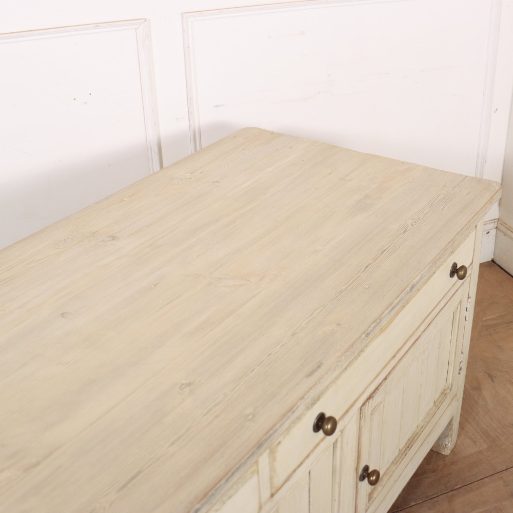 An English painted wood dresser base featuring two long top drawers with brass knob handles above panelled cupboard doors. View XI