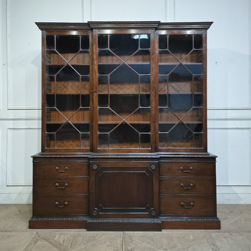 A large dark mahogany breakfront bookcase featuring astragal glazed upper doors, lower drawers, and a central cupboard door.