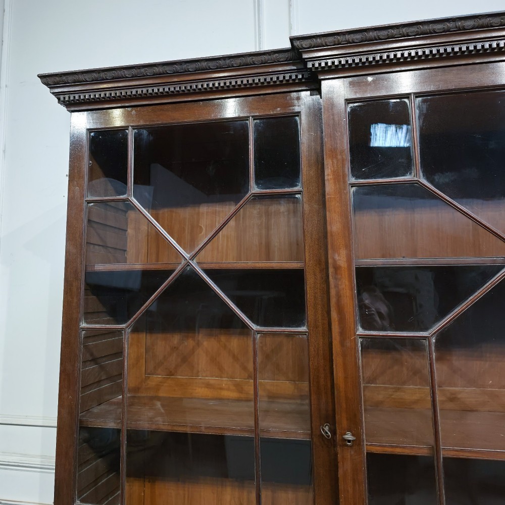 A large dark mahogany breakfront bookcase featuring astragal glazed upper doors, lower drawers, and a central cupboard door. View IV
