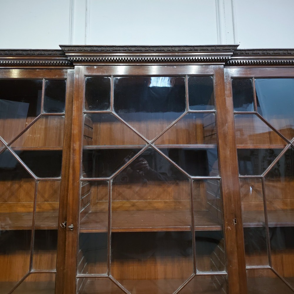 A large dark mahogany breakfront bookcase featuring astragal glazed upper doors, lower drawers, and a central cupboard door. View V