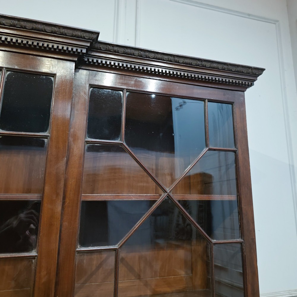 A large dark mahogany breakfront bookcase featuring astragal glazed upper doors, lower drawers, and a central cupboard door. View VI