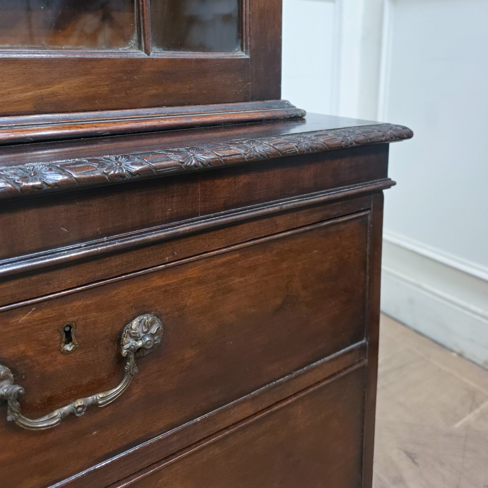 A large dark mahogany breakfront bookcase featuring astragal glazed upper doors, lower drawers, and a central cupboard door. View VII