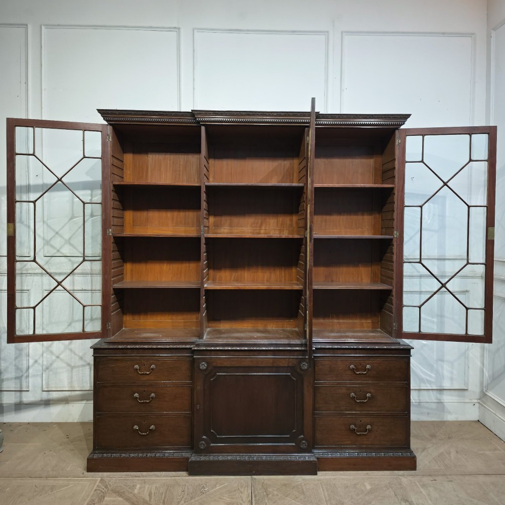 A large dark mahogany breakfront bookcase featuring astragal glazed upper doors, lower drawers, and a central cupboard door. View IX