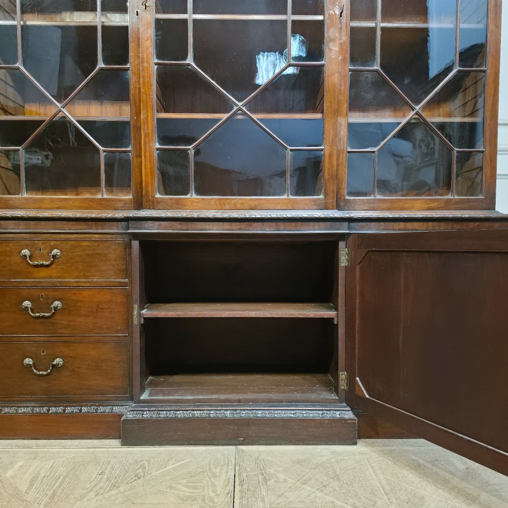 A large dark mahogany breakfront bookcase featuring astragal glazed upper doors, lower drawers, and a central cupboard door. View XI