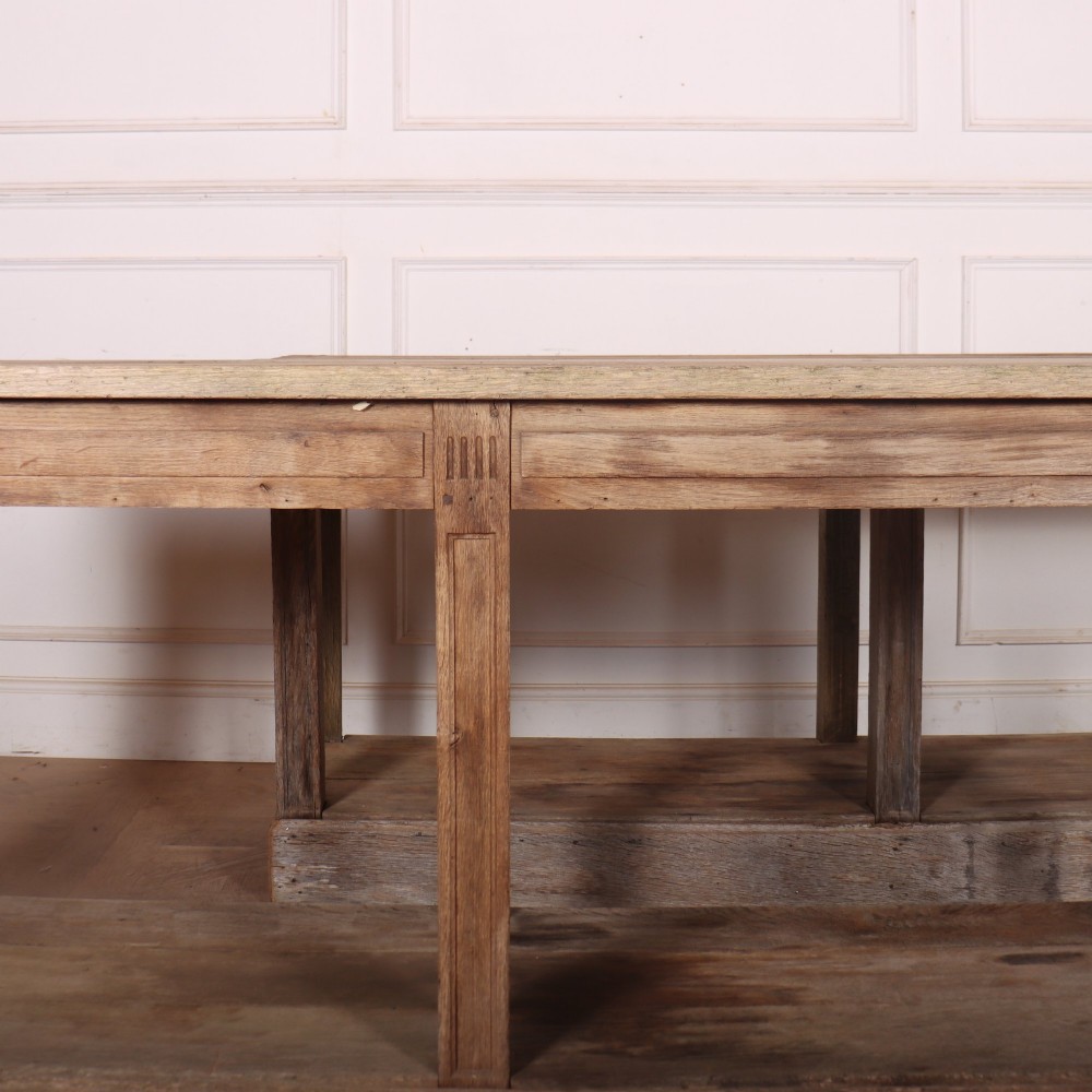 A pair of long rustic wooden French console tables with lower open shelves and weathered pale timber finish. View IV