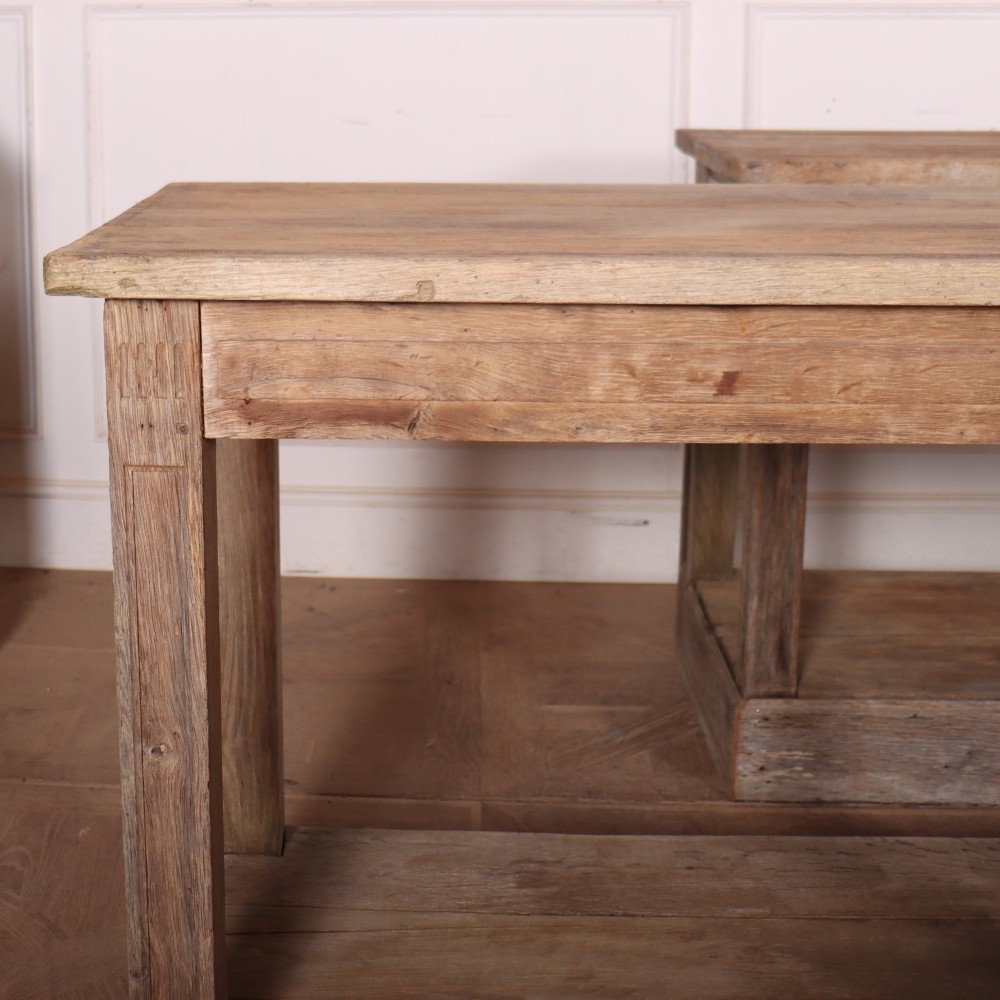 A pair of long rustic wooden French console tables with lower open shelves and weathered pale timber finish. View V