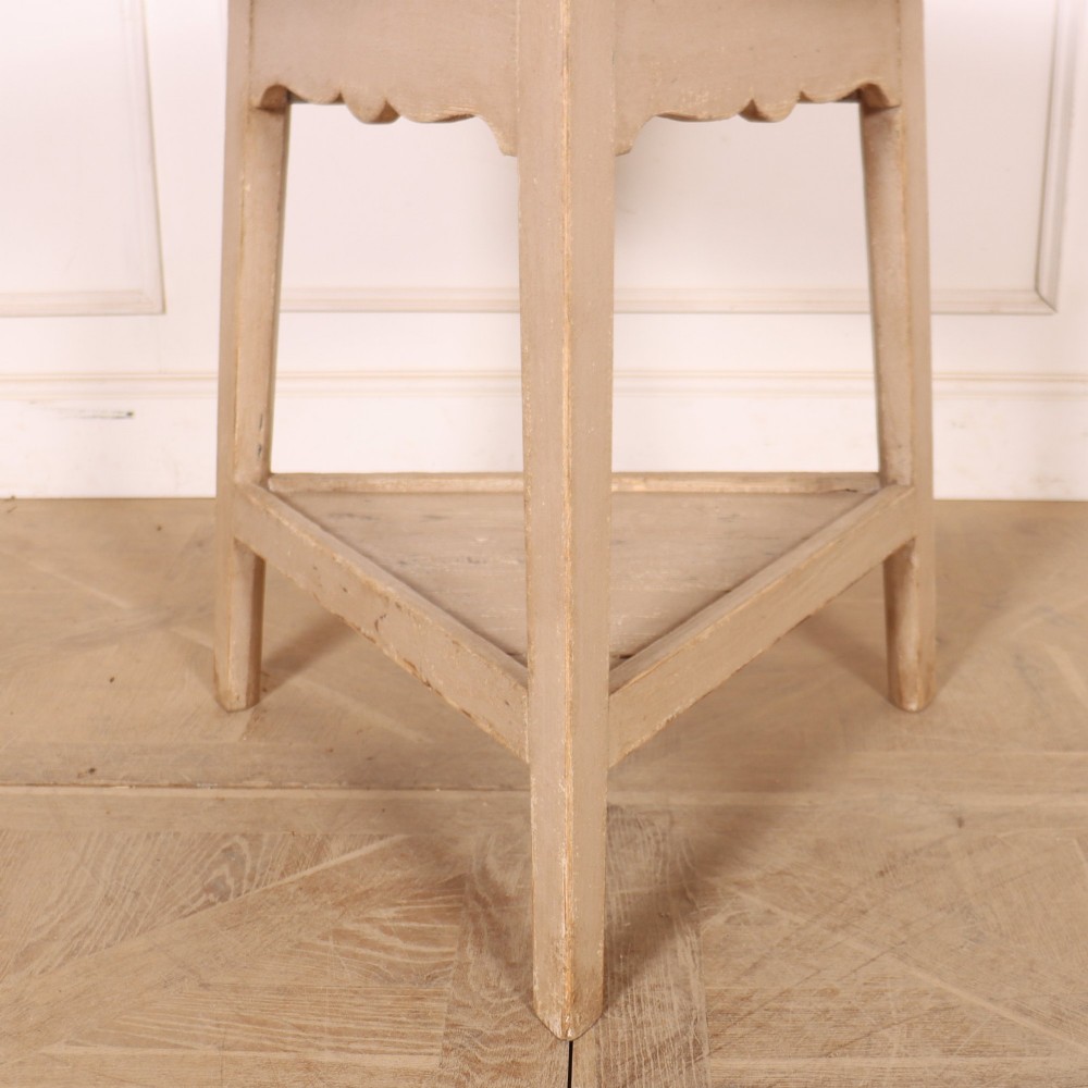 A nineteenth-century round wooden cricket table with three tapered legs, a lower triangular shelf, a scalloped apron, and a pale grey painted finish. View II