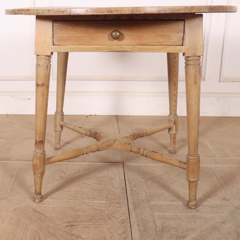 A 19th-century circular Welsh tavern table constructed from light pine with a frieze drawer, turned legs, and an X-frame stretcher. View II