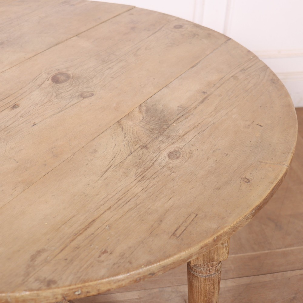 A 19th-century circular Welsh tavern table constructed from light pine with a frieze drawer, turned legs, and an X-frame stretcher. View VII