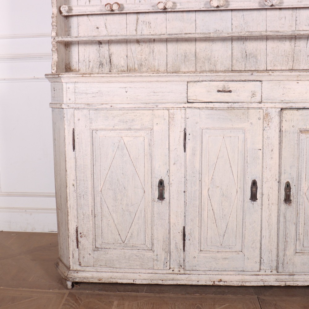 An antique off-white painted Danish pine dresser featuring an open tiered plate rack above a three-door cupboard base with diamond-moulded panels. View II