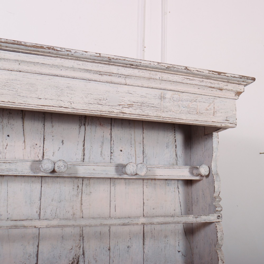 An antique off-white painted Danish pine dresser featuring an open tiered plate rack above a three-door cupboard base with diamond-moulded panels. View VI