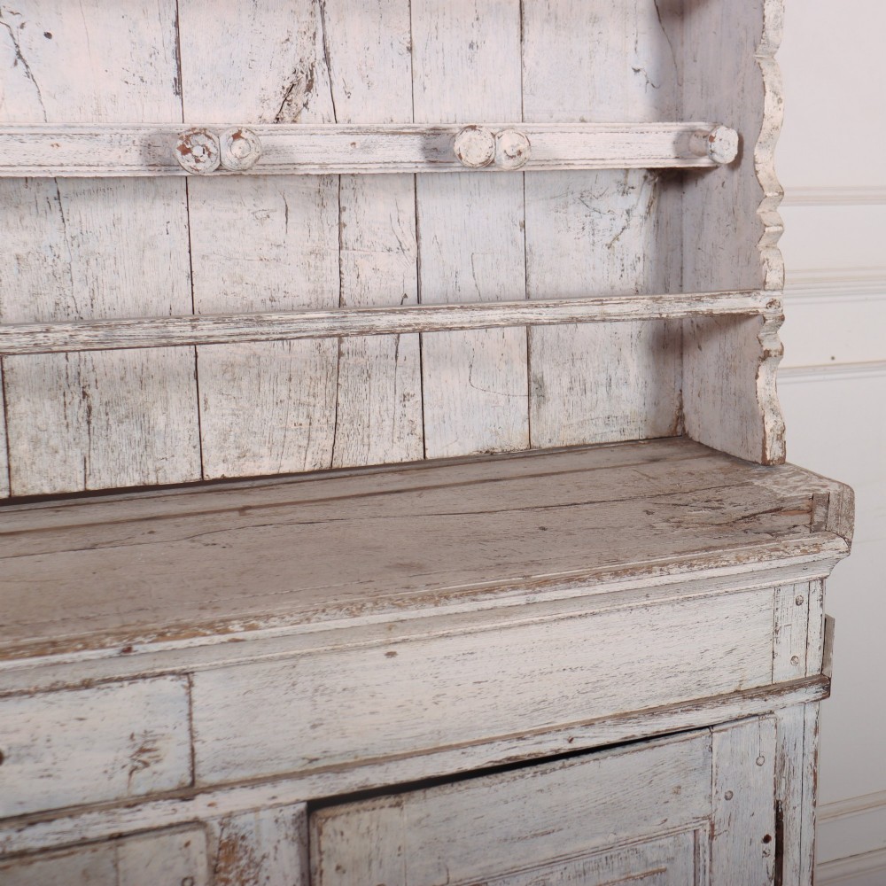 An antique off-white painted Danish pine dresser featuring an open tiered plate rack above a three-door cupboard base with diamond-moulded panels. View VII