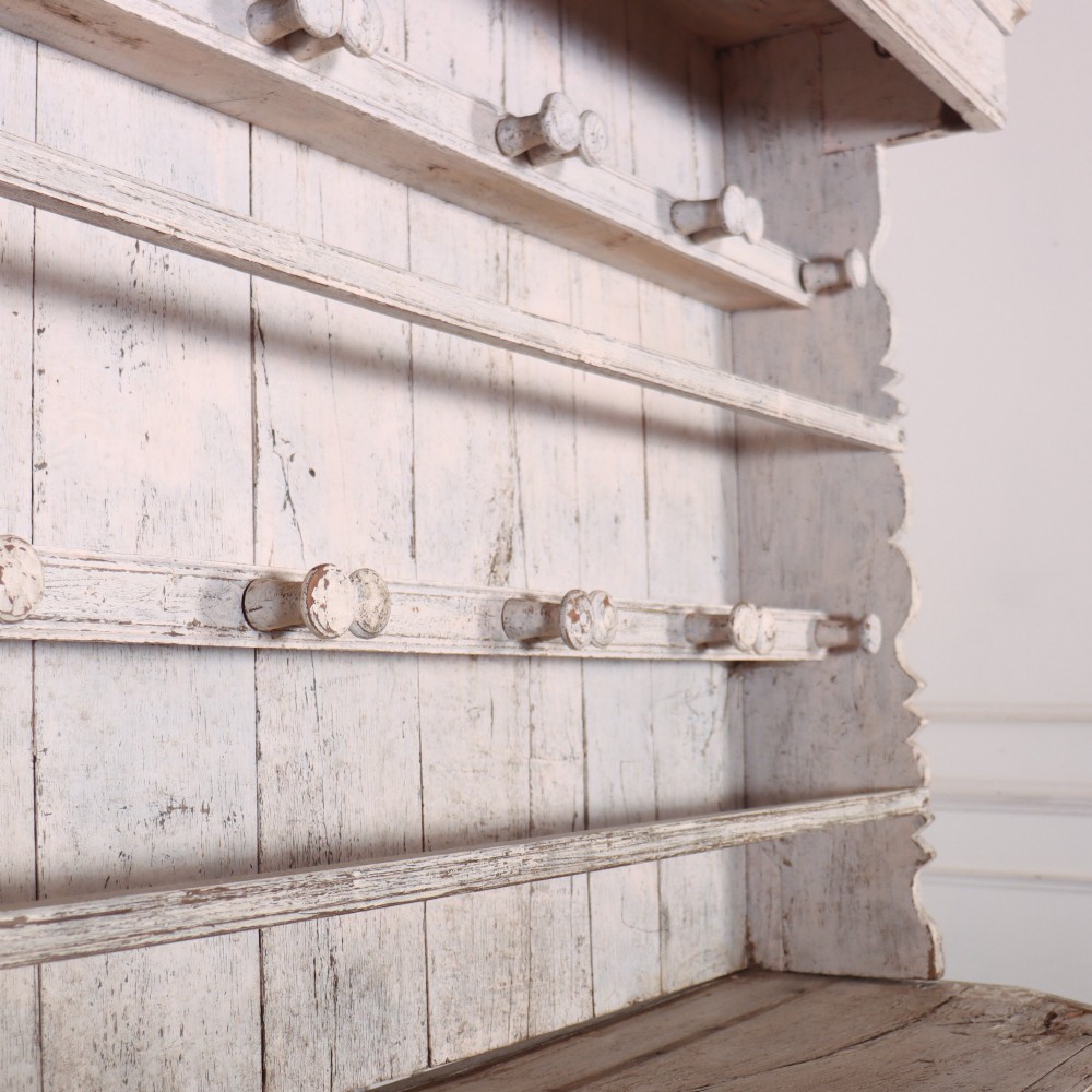 An antique off-white painted Danish pine dresser featuring an open tiered plate rack above a three-door cupboard base with diamond-moulded panels. View X