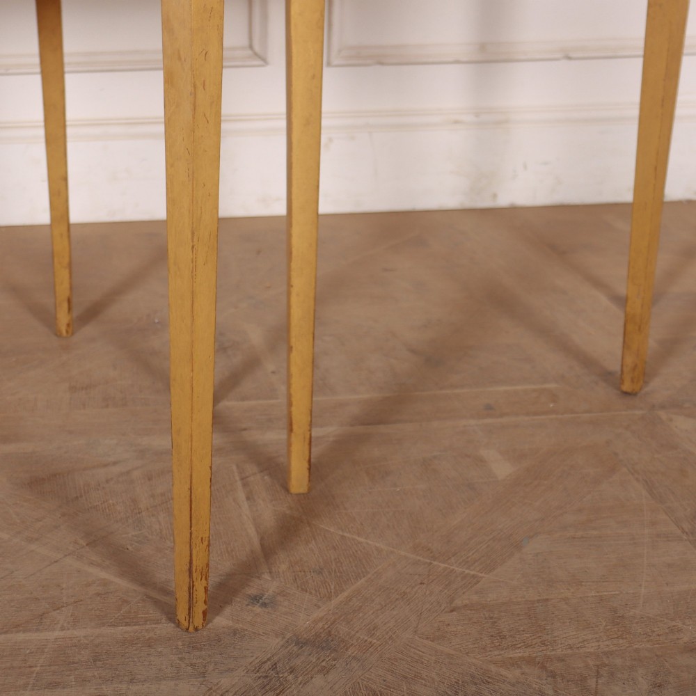 A pair of small painted demi-lune console tables with black tops, ochre yellow bases, and slender square tapered legs. View IV