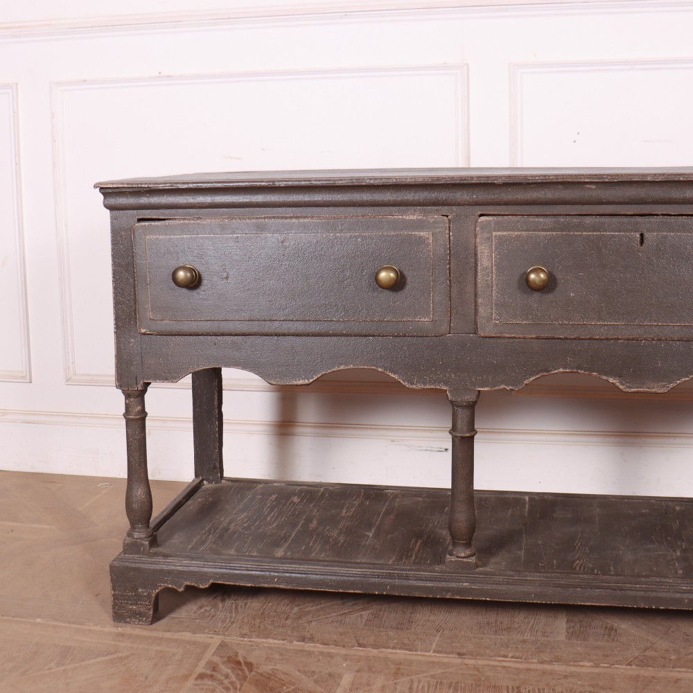 An English painted potboard dresser base in slate grey featuring three frieze drawers with brass handles and a low open shelf supported by turned legs. View II