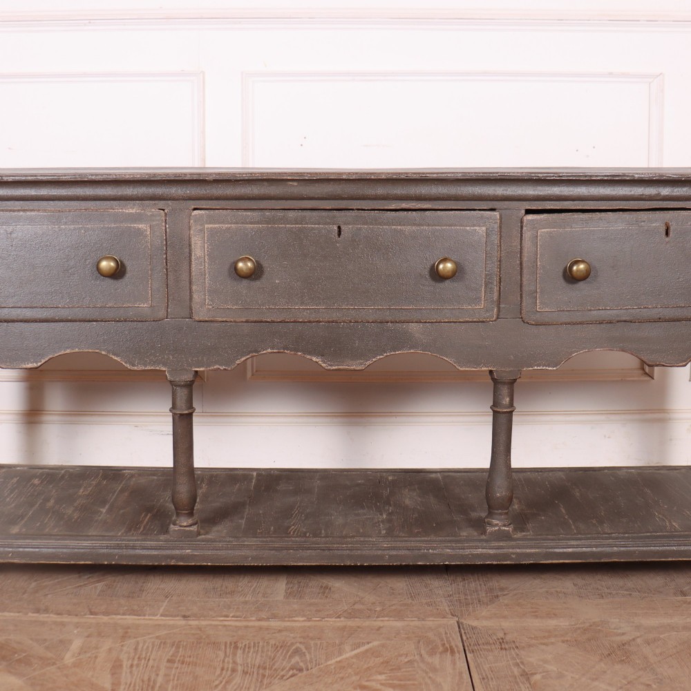 An English painted potboard dresser base in slate grey featuring three frieze drawers with brass handles and a low open shelf supported by turned legs. View III