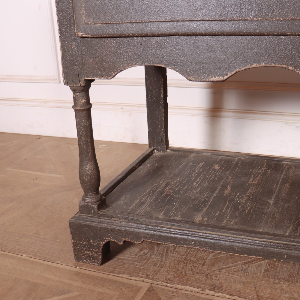 An English painted potboard dresser base in slate grey featuring three frieze drawers with brass handles and a low open shelf supported by turned legs. View V