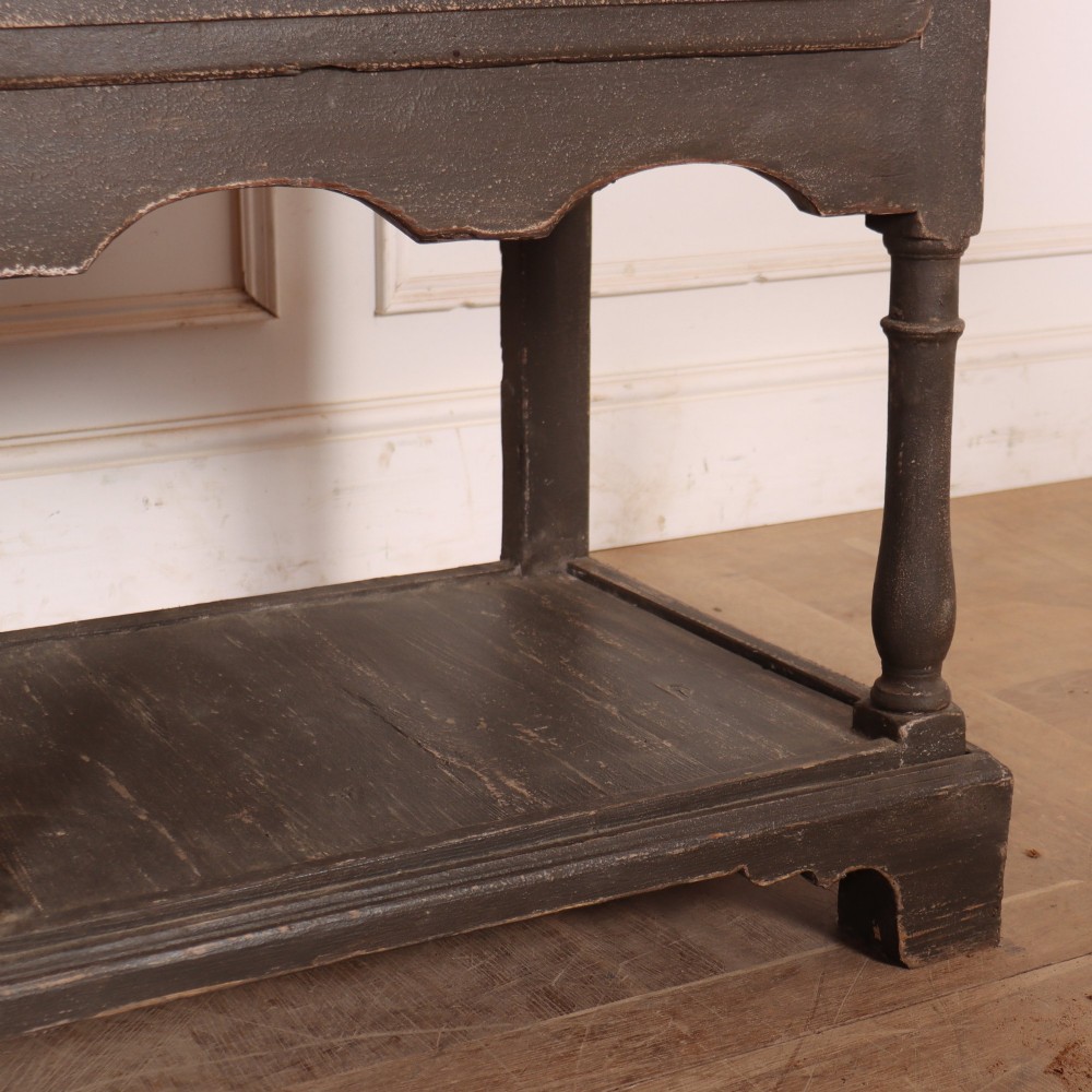 An English painted potboard dresser base in slate grey featuring three frieze drawers with brass handles and a low open shelf supported by turned legs. View VI