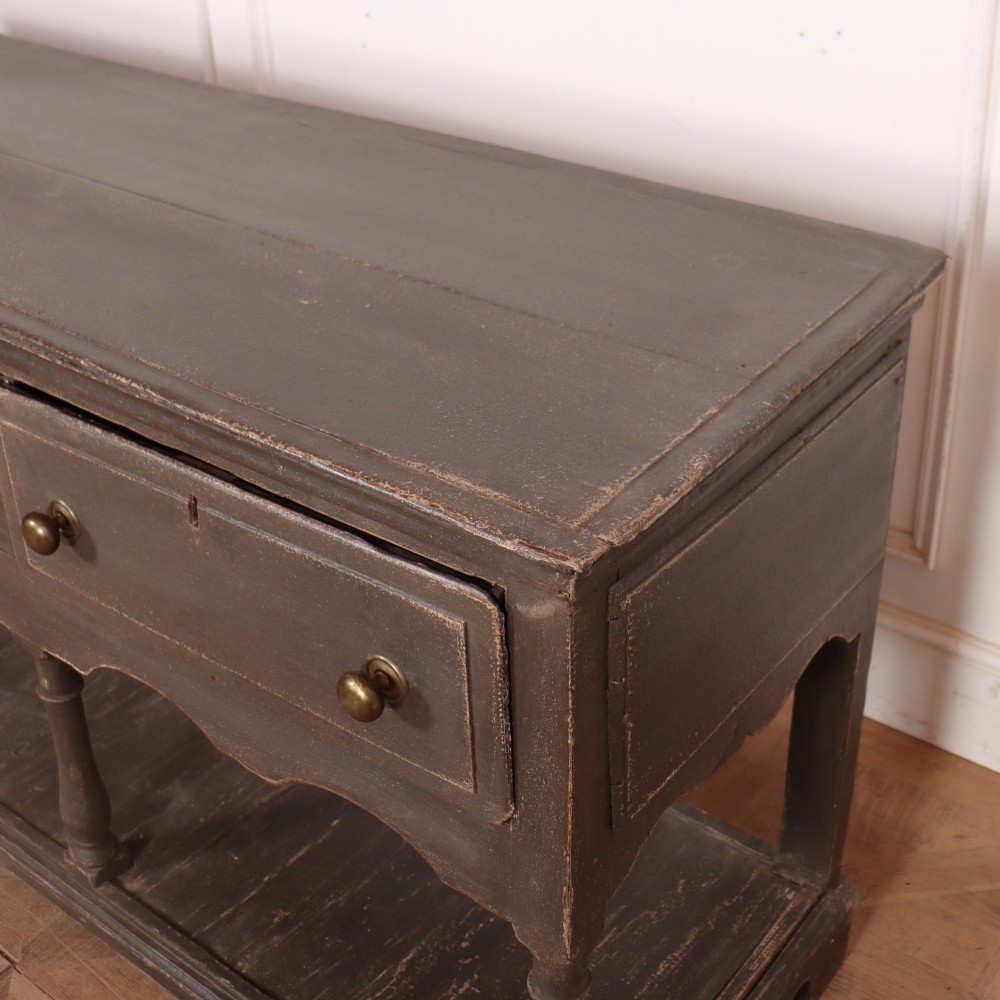 An English painted potboard dresser base in slate grey featuring three frieze drawers with brass handles and a low open shelf supported by turned legs. View VII