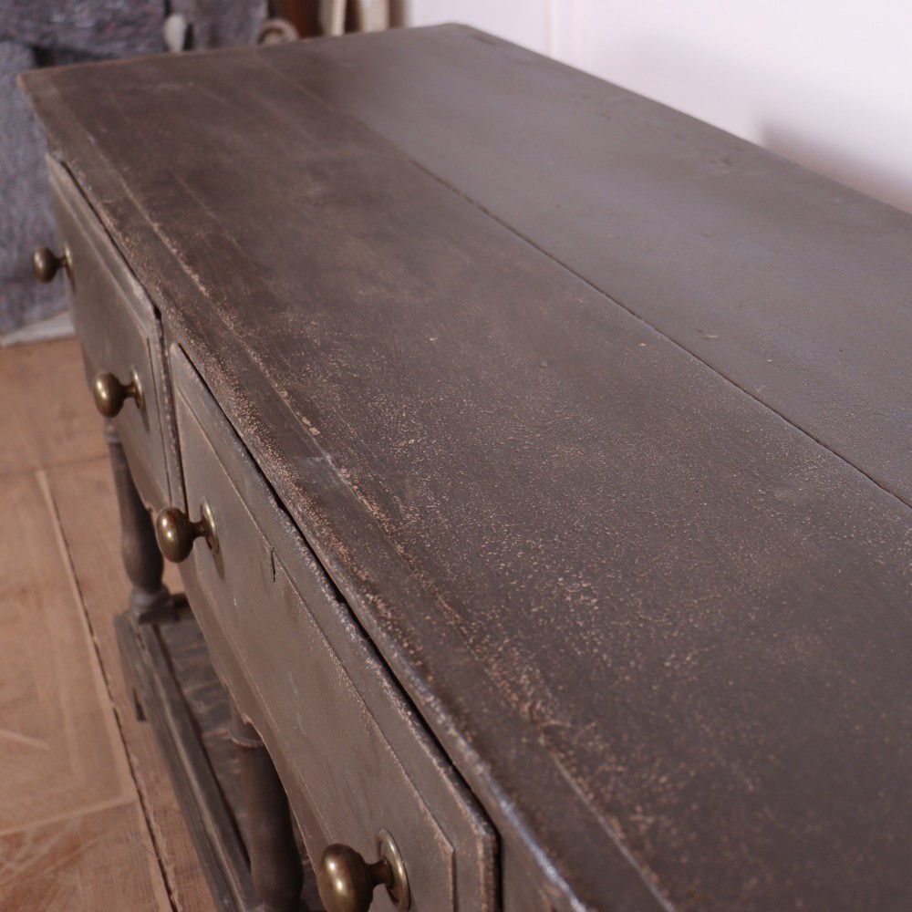 An English painted potboard dresser base in slate grey featuring three frieze drawers with brass handles and a low open shelf supported by turned legs. View VIII