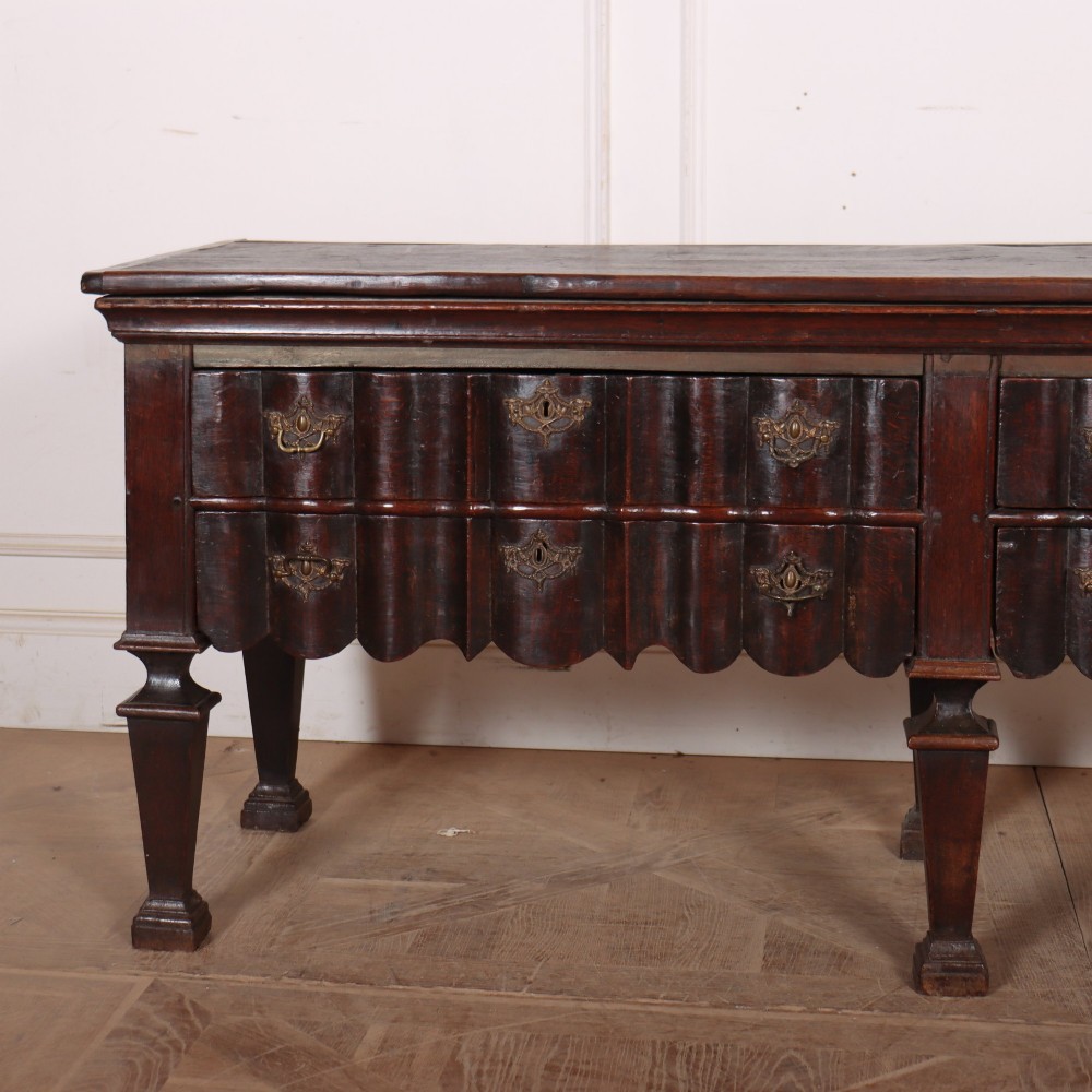 An antique dark oak Dutch dresser base with fluted drawer fronts, brass hardware, and turned legs. View II